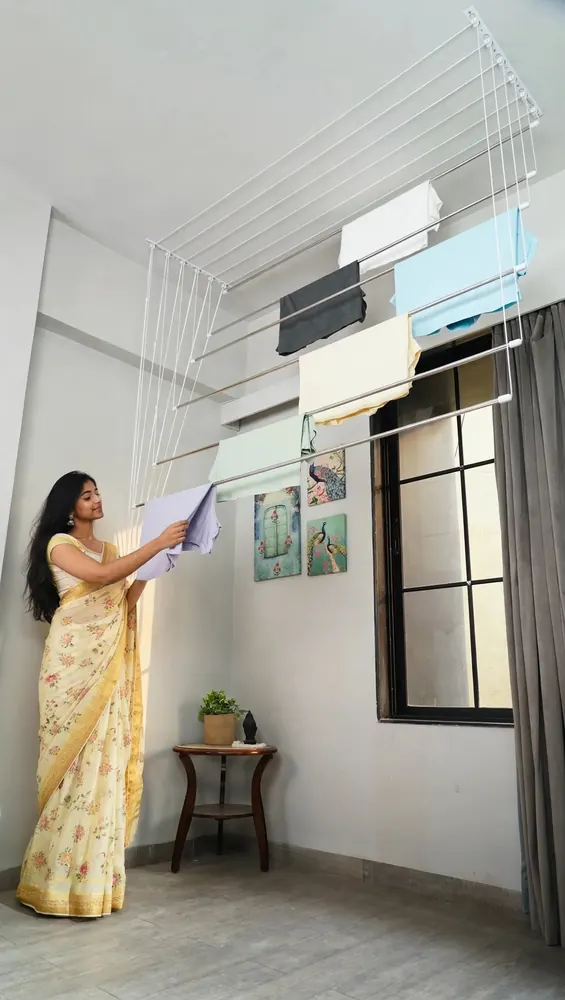 Woman hanging clothes on a ceiling cloth drying hanger on a balcony